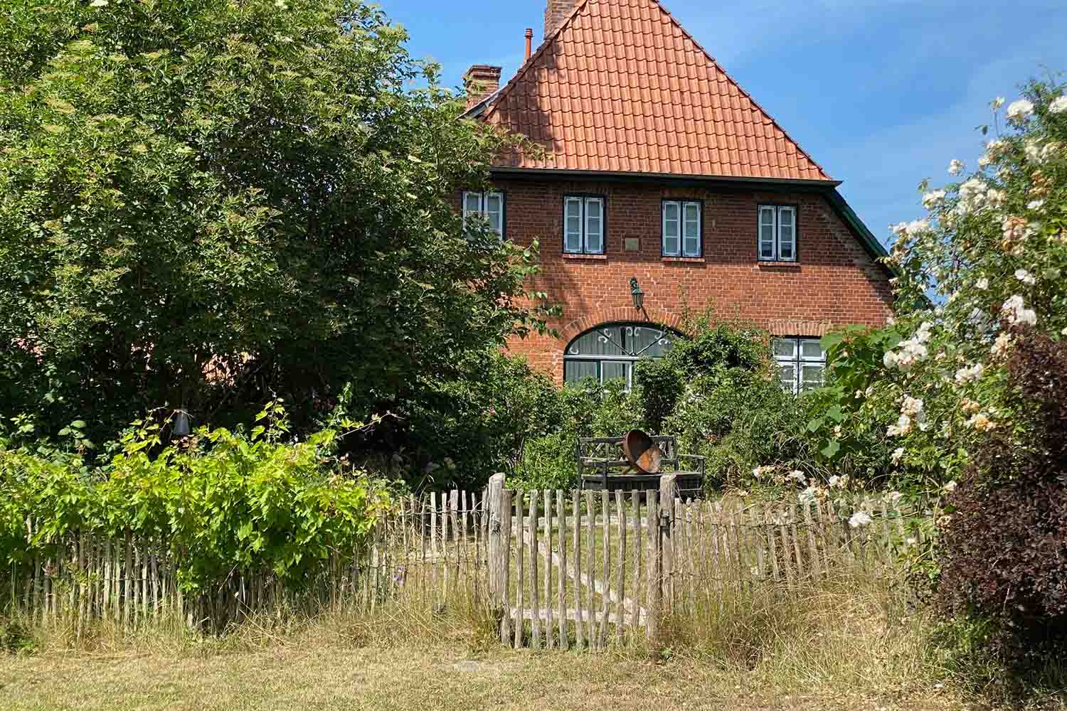 Backsteinhaus mit grünem Tor und blühendem Garten in Pronstorf