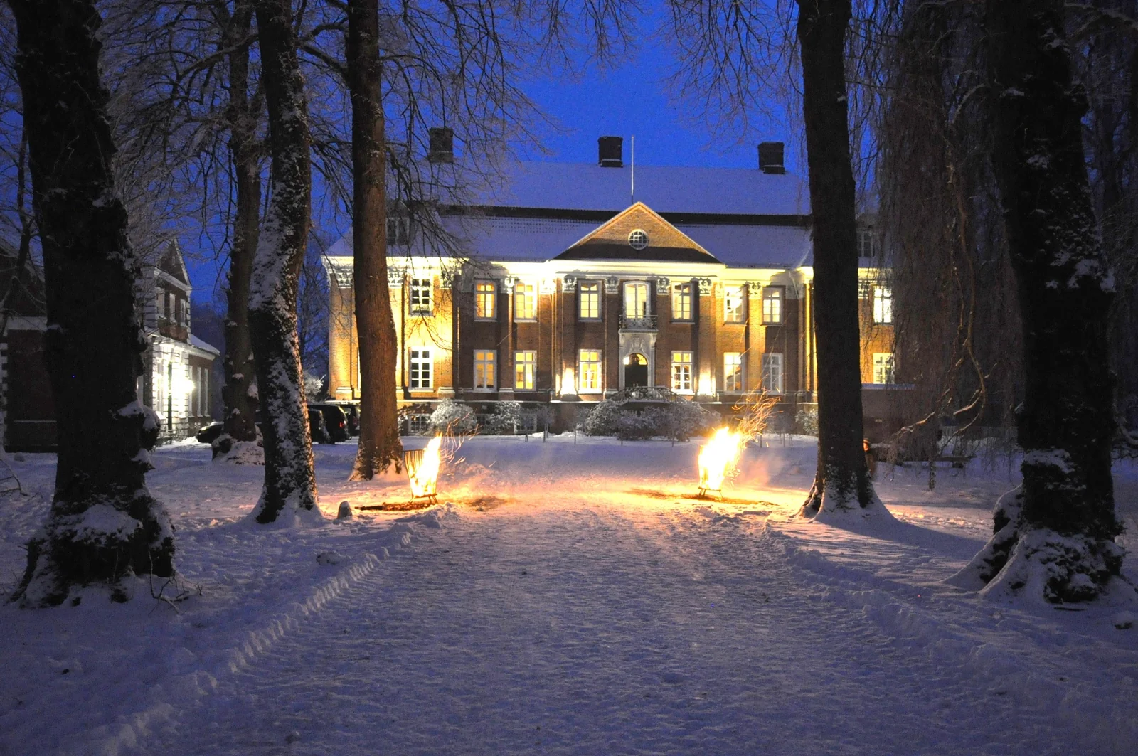 Feuerkörbe im Schnee vor dem beleuchteten Herrenhaus von Gut Pronstorf