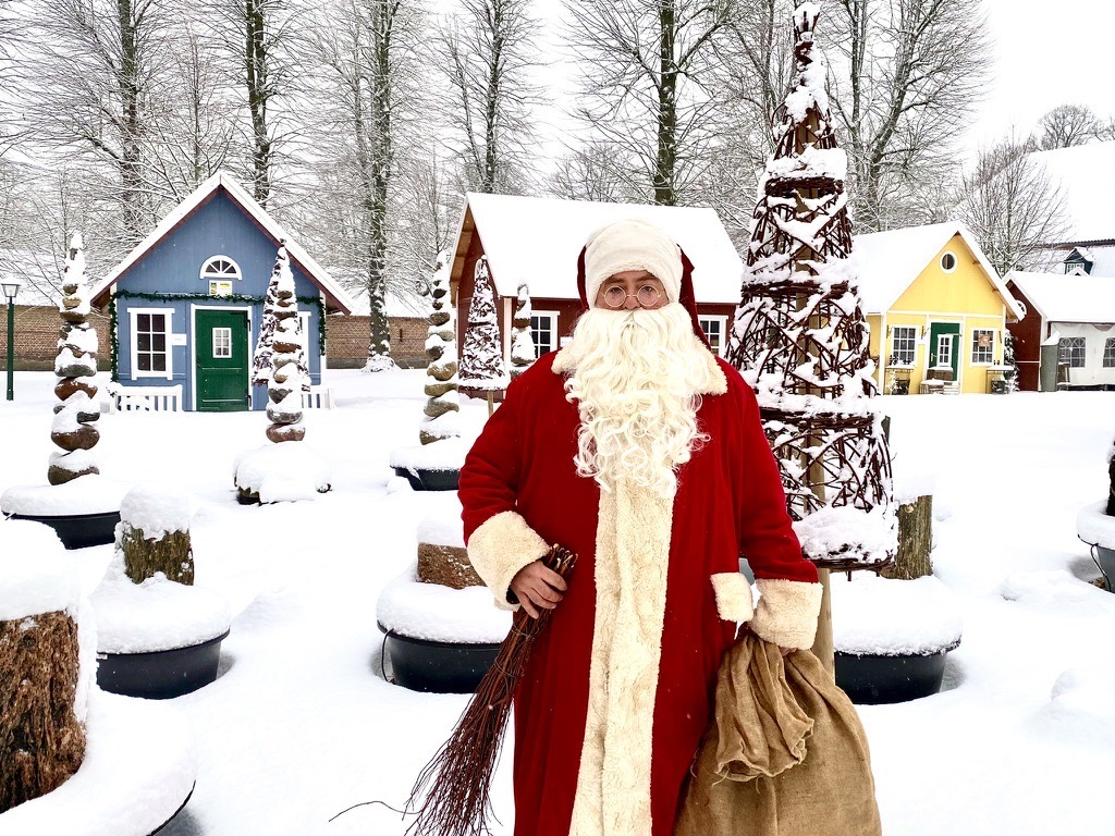 Der Weihnachtsmann vor den verschneiten Holzhäusern auf Gut Pronstorf